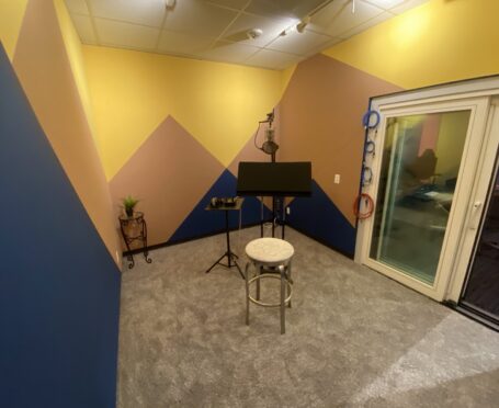 photo of the recording booth in our new Dolly Parton suite. Professional microphone sits in the center of spacious recording booth with colorful walls inspired by the Rocky Mountains.