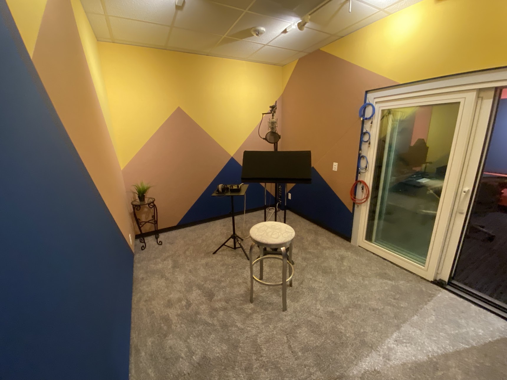 photo of the recording booth in our new Dolly Parton suite. Professional microphone sits in the center of spacious recording booth with colorful walls inspired by the Rocky Mountains.
